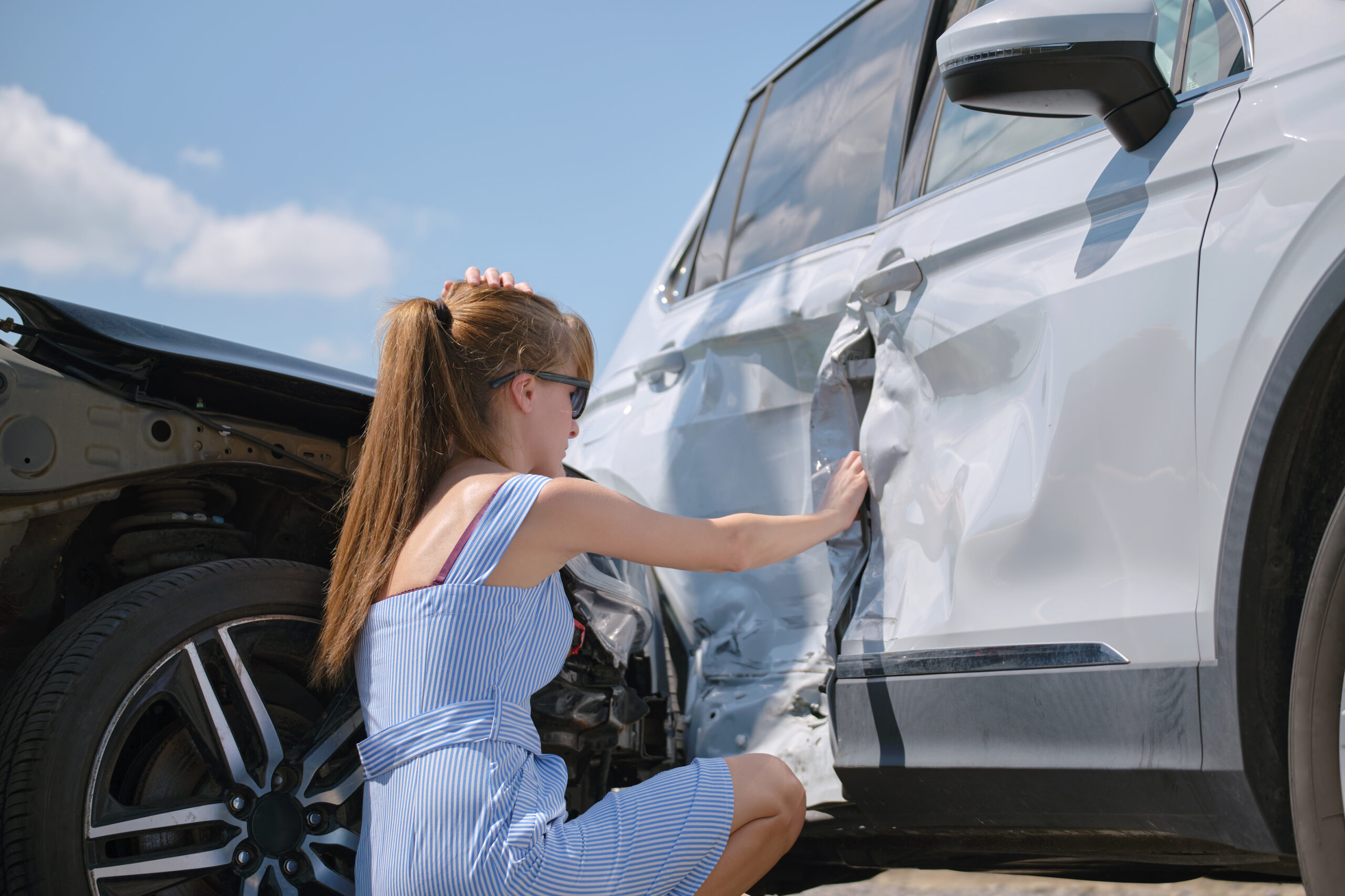 Woman touching her damaged car after an accident